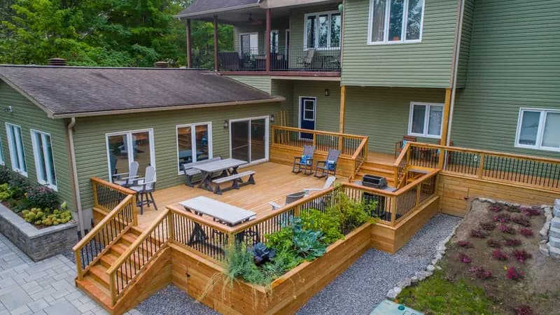 A multi-level timber deck with railings and steps down to a planted garden