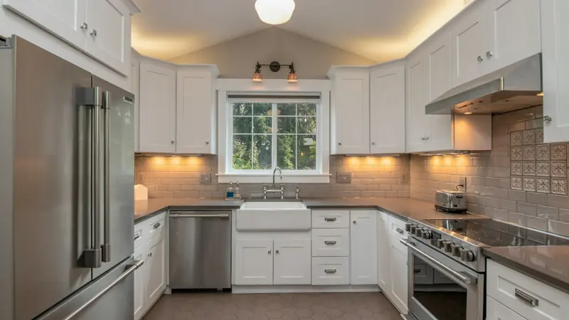 A fitted kitchen with white cabinetry, pendant lighting and a tiled splashback